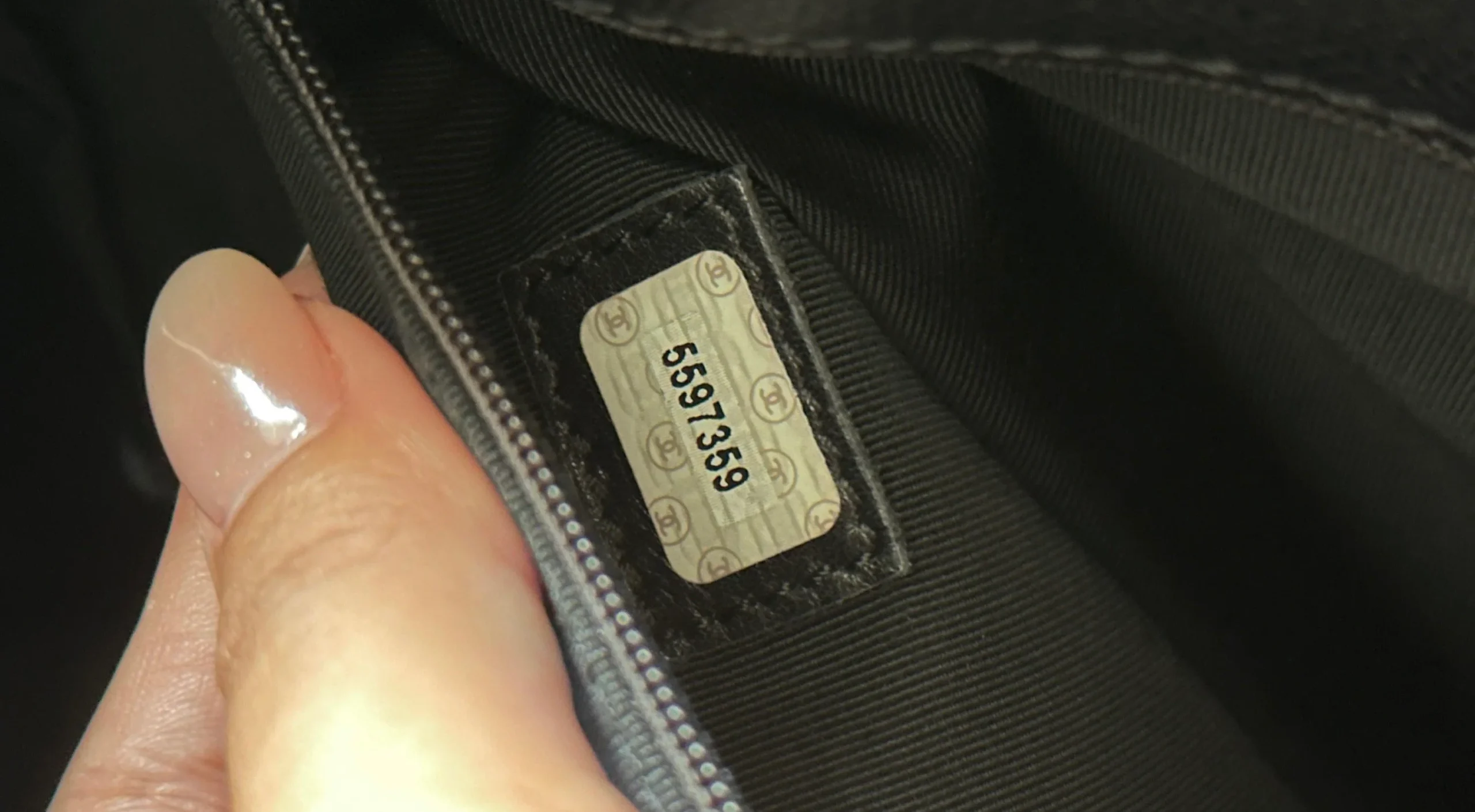 Authentic vintage Chanel serial number sticker with X-cut and gold speckling inside a leather bag.